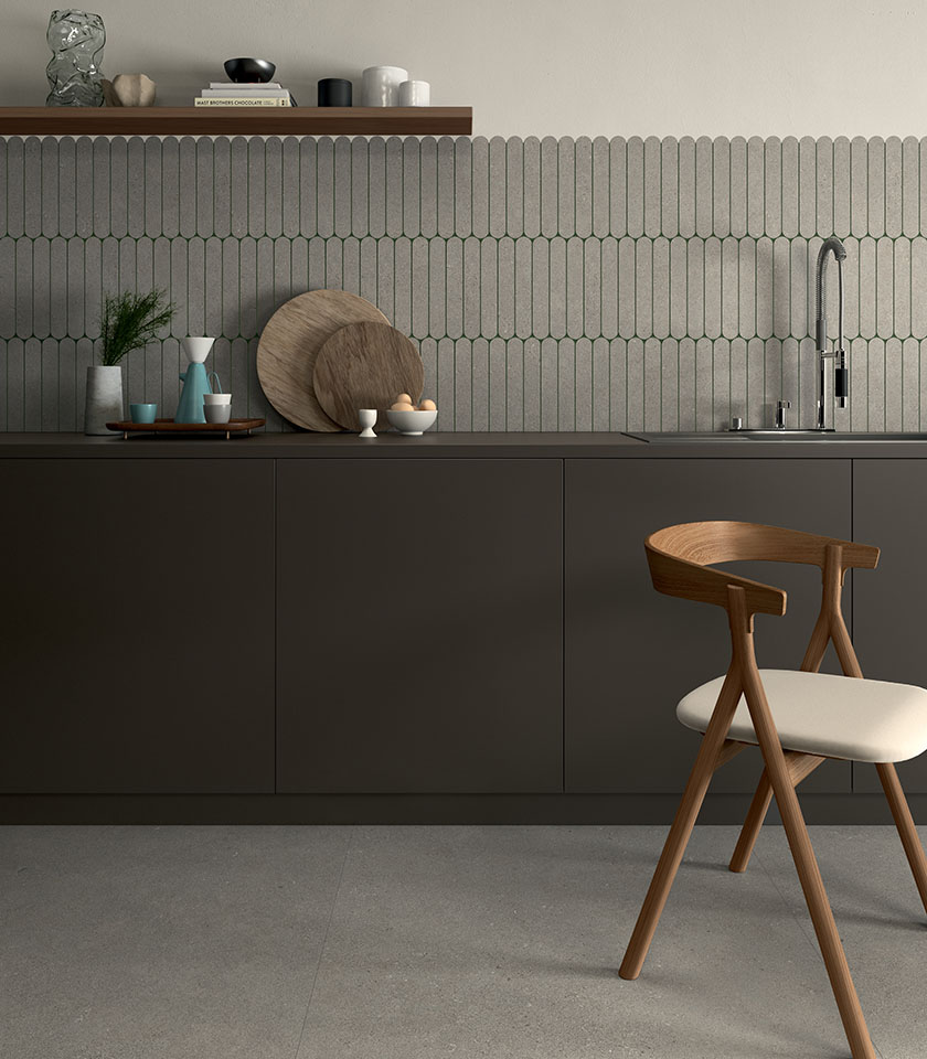 Minimal chic kitchen with concrete-effect flooring, tone-on-tone geometric wall tiles, dark cabinetry and essential wooden design details.