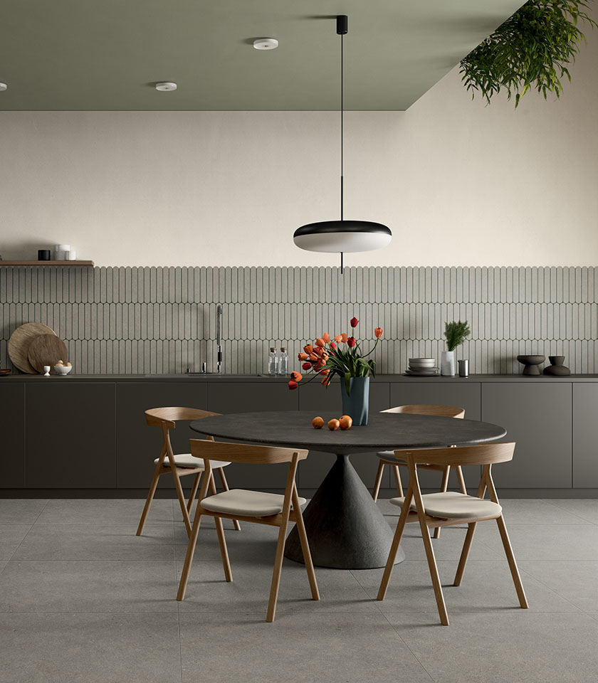 Contemporary dining area with a dark table and wooden chairs, featuring flooring from the Intense collection in Crete Clair stone effect and Pills Crete decorative wall tiles.