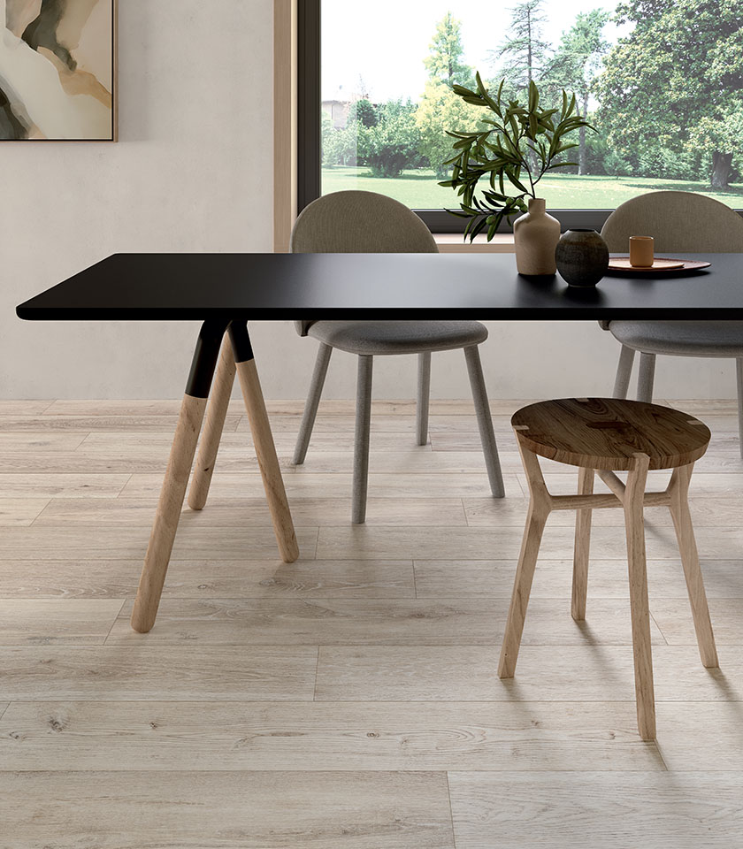 Contemporary dining area with a black table and wooden seating, featuring flooring from the Bio Attitude collection with a wood effect in the Cotton shade.