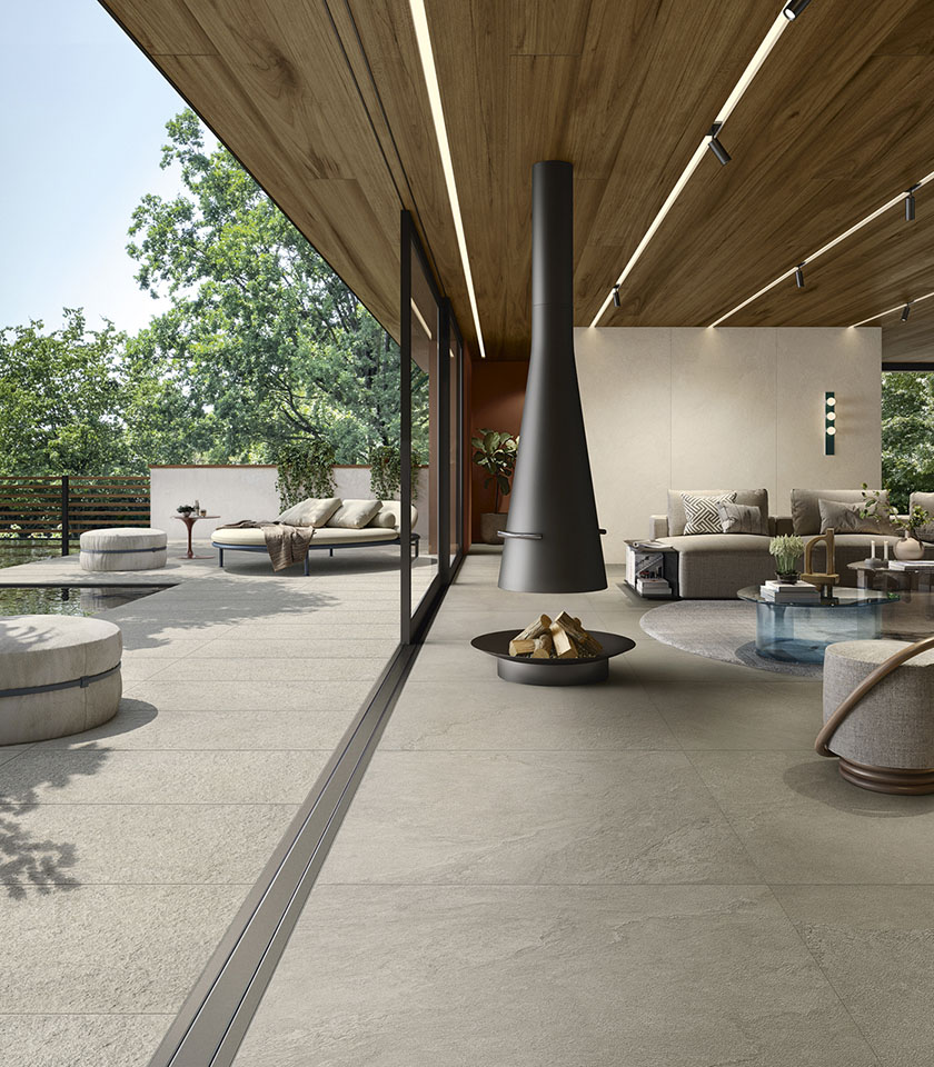 Contemporary indoor-outdoor living space with flooring from the Pulse collection in Clay stone effect, Clay Rough finish for the outdoor area and wall coverings in the Shell shade.