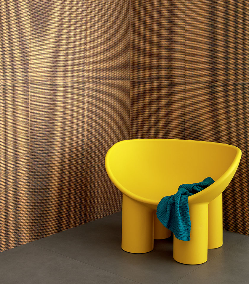 Contemporary bathroom interior with orange and black decorative wall covering, a yellow armchair and blue textile details.