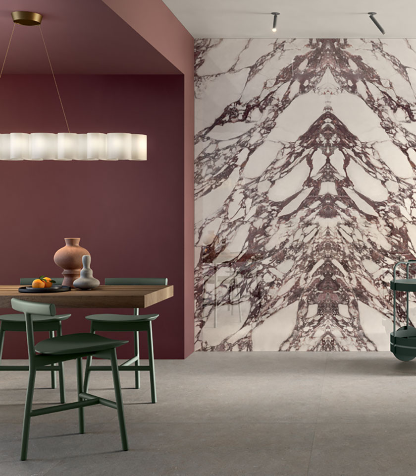 Contemporary dining room with a marble-effect feature wall, burgundy tones, wooden table and green chairs.