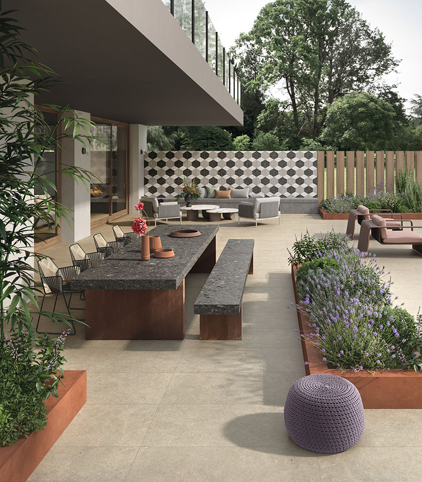 Contemporary outdoor space with flooring from the Intense collection in Toffee stone effect, Sidestone Cluster Dark surfaces, a decorative wall with Sidestone Omega mosaic and Pigmenti Canyon elements.