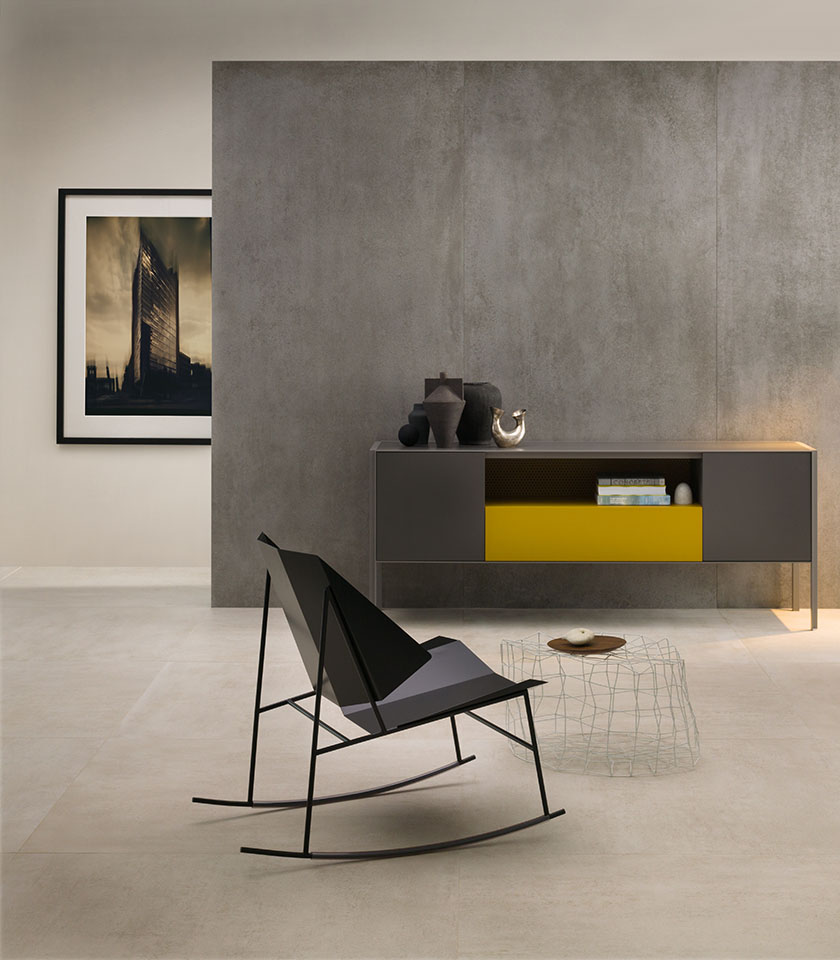 Minimal chic living space with light concrete-effect flooring, large-format grey wall tiles, essential furnishings and contemporary design details.