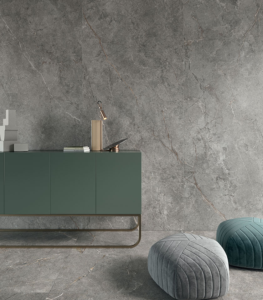 Large-format dark stone-effect porcelain stoneware flooring, viewed from above with a side table, seating and decorative accessories.